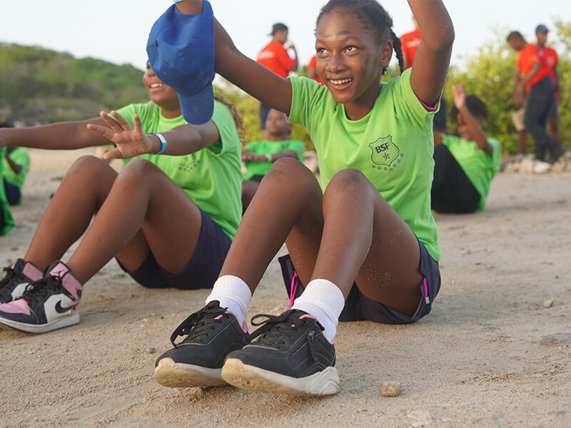 Kinderen in sportshirts doen buitenoefeningen op het strand